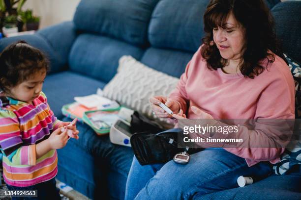 hispanic grandmother and grand daughter playing together at home - childhood diabetes stock pictures, royalty-free photos & images