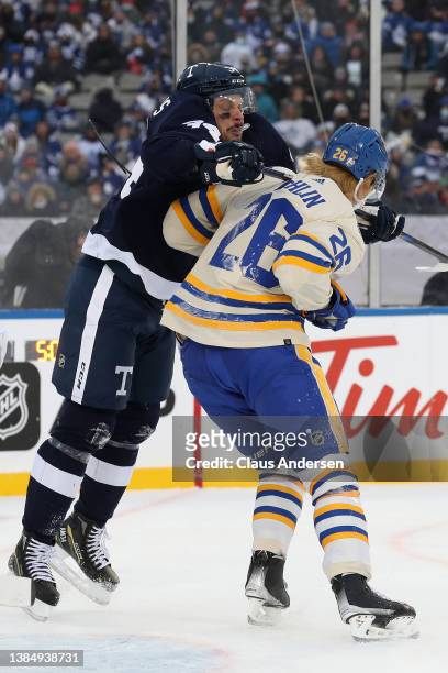Morgan Rielly of the Toronto Maple Leafs cross checks Rasmus Dahlin of the Buffalo Sabres in the third period during the Heritage Classic at Tim...