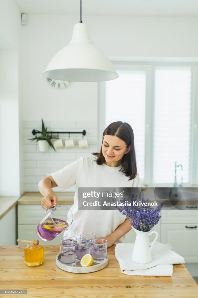 Honey, glasses with ice, lemon juice and lavender cocktail on kitchen table.