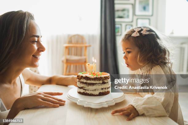 young girl with his mother blowing candles for celebreating her 2th years birthday. - carrot cake stock pictures, royalty-free photos & images