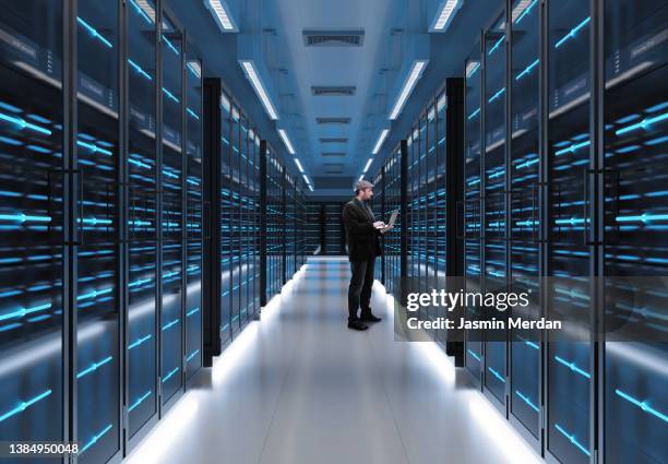 man working on laptop in server room - server room stock pictures, royalty-free photos & images