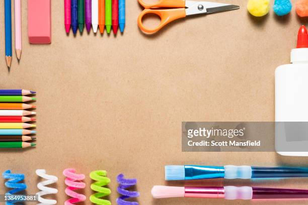 brown kraft paper background with a colorful border of neatly arranged art and craft supplies - possible stock pictures, royalty-free photos & images