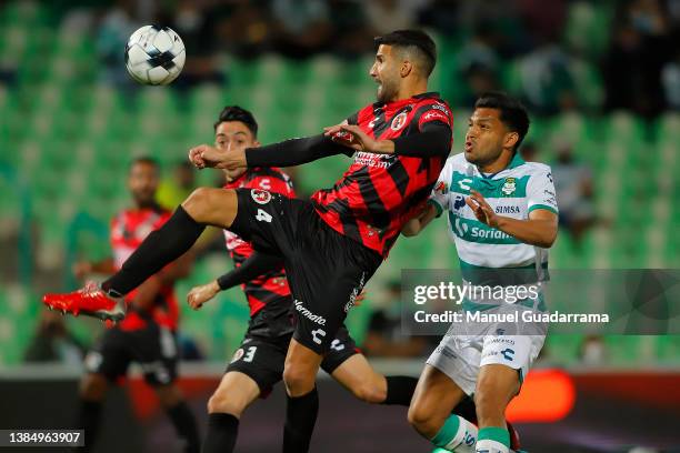 Lisandro Lopez of Tijuana struggles for the ball with Eduardo Aguirre of Santos during the 10th round match between Santos Laguna and Club Tijuana as...
