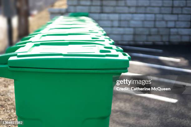 row of municipal green community composting bins - vuilnisemmer op wielen stockfoto's en -beelden
