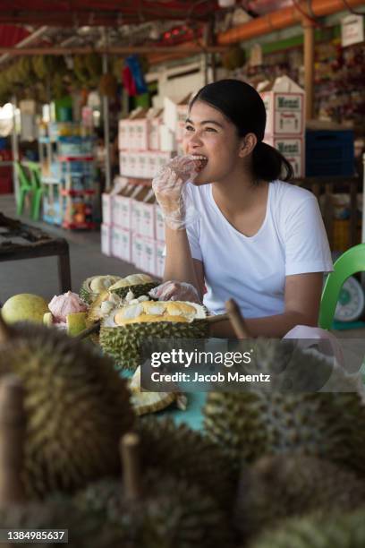 a local woman eats durian at a fruit stall in davao city, philippines. - filipino women stock pictures, royalty-free photos & images