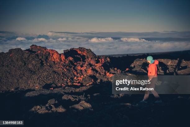 a woman hikes across a lava field high above the clouds on a hawaiin volcano - mauna loa stock pictures, royalty-free photos & images