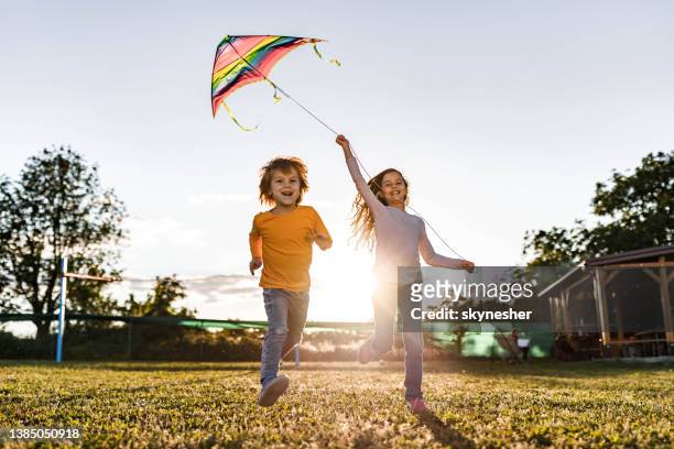 carefree little kids running with a kite in the backyard. - vlieger stockfoto's en -beelden