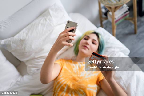 young woman with colored hair is shopping online with a credit card - money decisions stock pictures, royalty-free photos & images