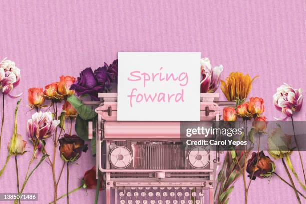 spring forward text in pink typewriter with some fresh flowers around - spring forward fotografías e imágenes de stock