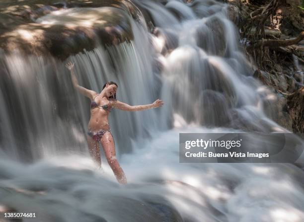 woman taking a shower under a waterfall - dunns river falls stock pictures, royalty-free photos & images