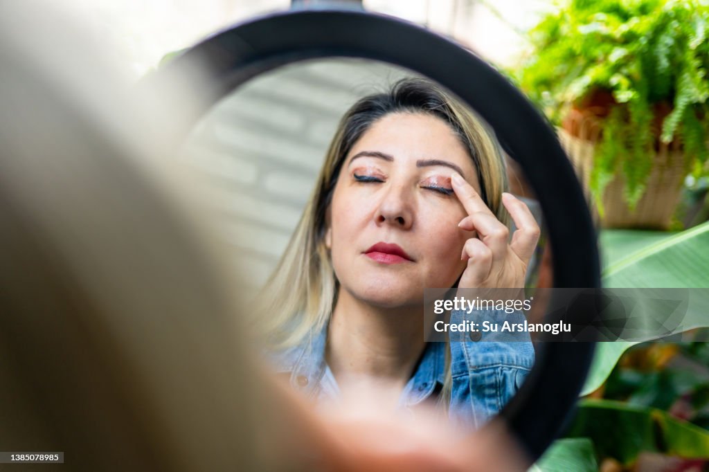 Woman having eyelid surgery applies eye cream at home