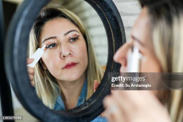 woman having eyelid surgery applies eye cream at home - blepharisma stockfoto's en -beelden