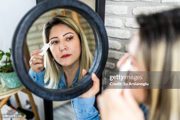 woman having eyelid surgery applies eye cream at home - blepharisma stockfoto's en -beelden