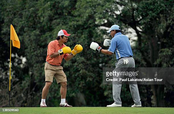 Filipino professional boxer and politician Manny Pacquiao and player partner Frankie Minoza of the Philippines pose in a mock spar on the 8th green...
