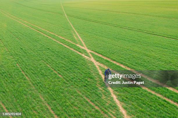 drone view of a cyclist on trail through field - alternative view stock-fotos und bilder