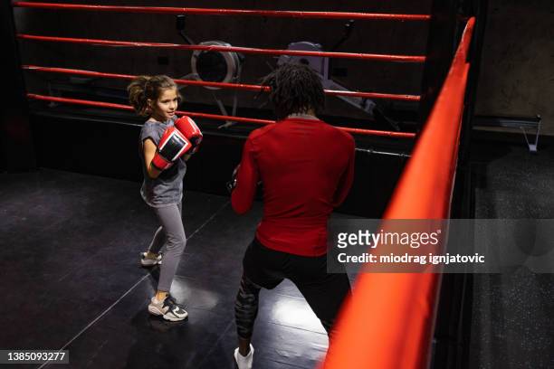 strong little girl sparring with her male boxing coach black ethnicity - child punching stock pictures, royalty-free photos & images