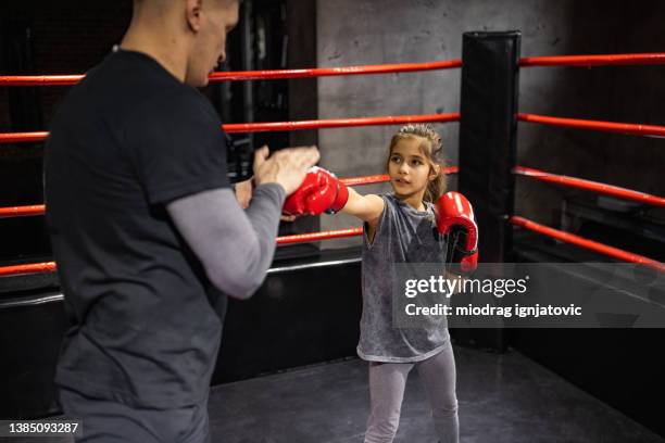 llittle girl practicing kickboxing with her male coach in health club - kickboxing equipment stock pictures, royalty-free photos & images