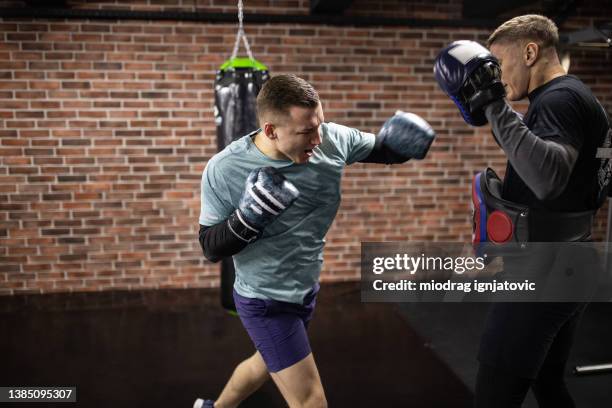 forte pugile maschio di etnia caucasica, con un allenamento di kickboxing con il suo allenatore - sparring foto e immagini stock