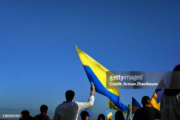 people holding yellow and blue flag of ukraine in front of the cloudy sky - ukraine war foto e immagini stock