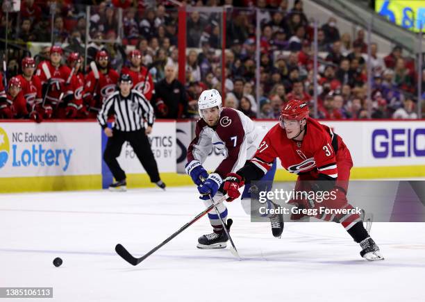 Andrei Svechnikov of the Carolina Hurricanes battles for a loose puck with Devon Toews during an NHL game against the Colorado Avalanche on March 10,...