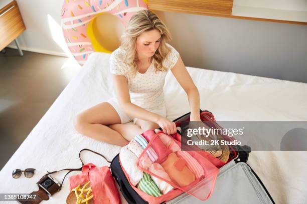 a young woman with blond long hair is packing her suitcase - suitcase packing stockfoto's en -beelden