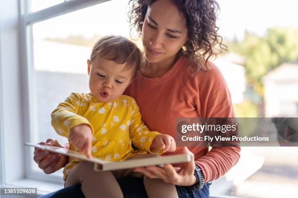 livre de lecture de mère affectueuse avec adorable fille en bas âge - mum with baby photos et images de collection