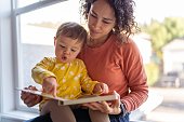 Affectionate mother reading book with adorable toddler daughter