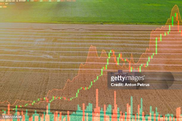 aerial view of combine harvesters on the background of stock charts. the concept of rising prices for grain and food - agricultural equipment imagens e fotografias de stock