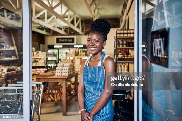 shot of a confident young woman standing in the doorway of her organic store - market vendor imagens e fotografias de stock