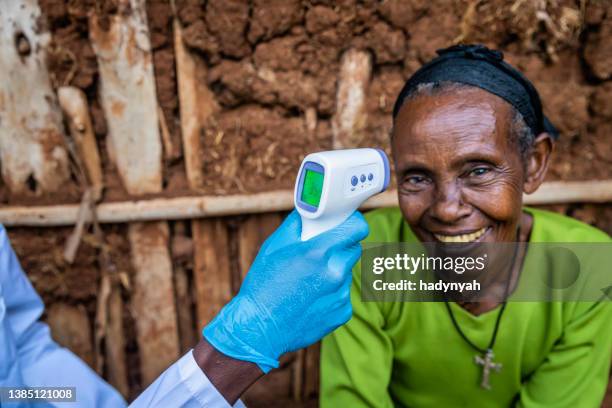 male doctor taking senior woman temperature in remote village, east africa - 3rd world stock pictures, royalty-free photos & images