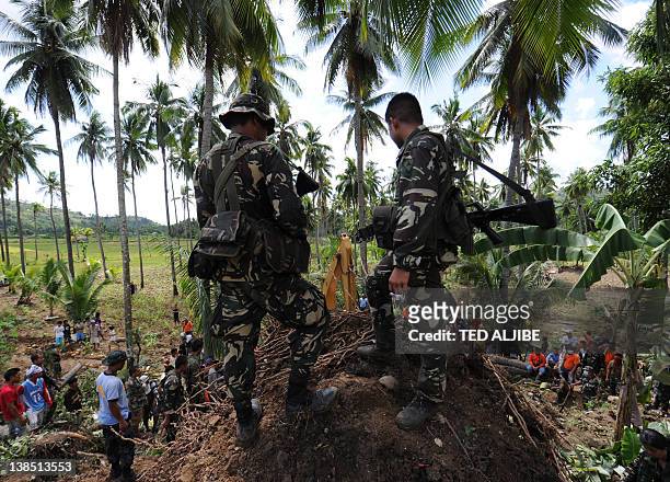 Philippine soldiers watch as recuers using a backhoe dig for survivors during a retrieval operation on the slope of a mountain which collapsed at the...