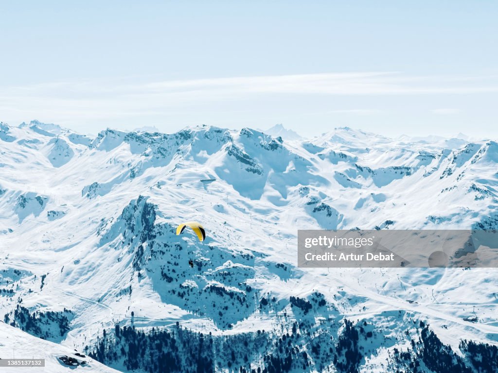 Paragliding the beautiful French Alps covered with snow and blue colors.