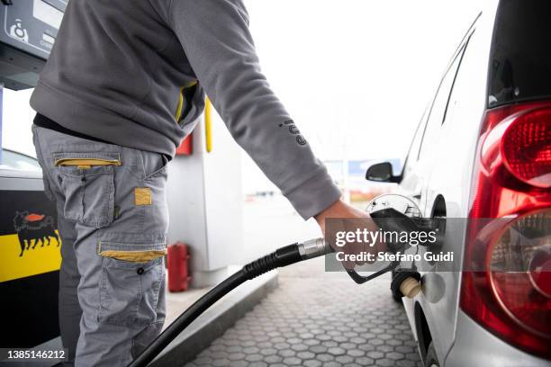 Fuel man refueling a car with gasoline at a petrol station on March 14, 2022 in Turin, Italy. Oil and gas prices are hitting record highs across...