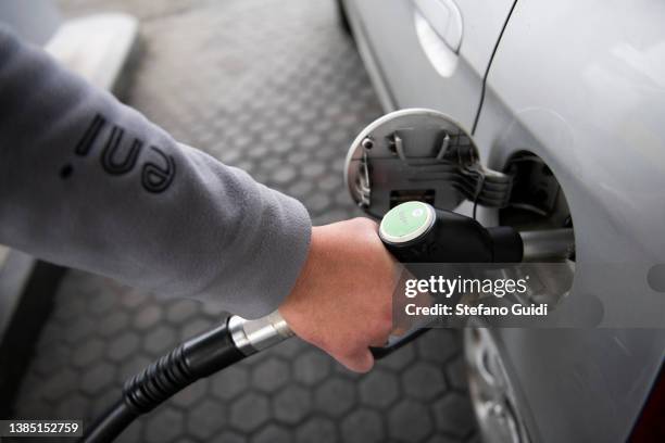 Hand of fuel man refueling a car with gasoline at a petrol station on March 14, 2022 in Turin, Italy. Oil and gas prices are hitting record highs...