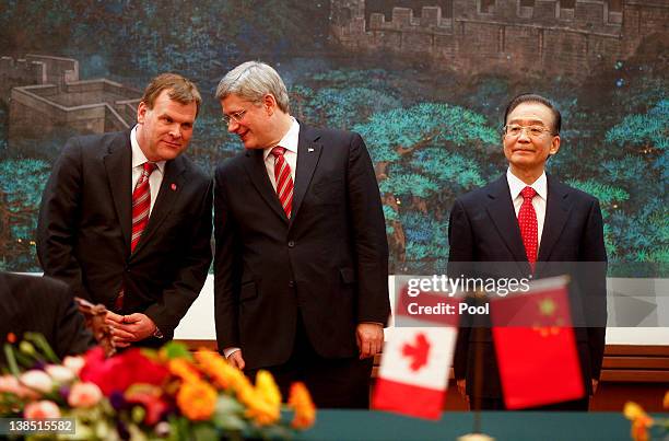 Canadian Foreign Minister John Baird whispers to Canadian Prime Minister Stephen Harper while standing next to Chinese Premier Wen Jiabao during a...