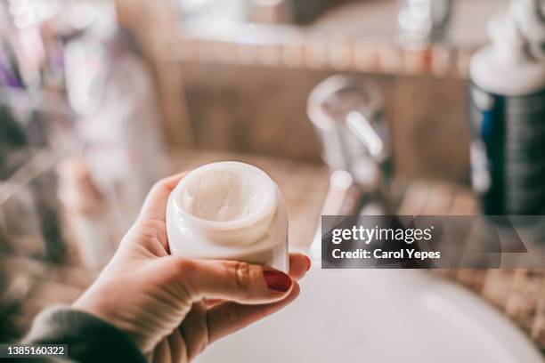 female hand with facial anti age  cream.bathroom gives space to copy - applying cream stock pictures, royalty-free photos & images