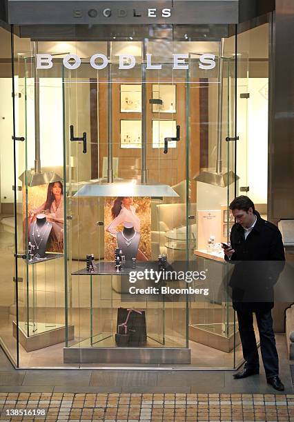 Visitor checks his mobile phone outside the Boodles jewellery store at the Royal Exchange luxury shopping and dining arcade in London, U.K., on...