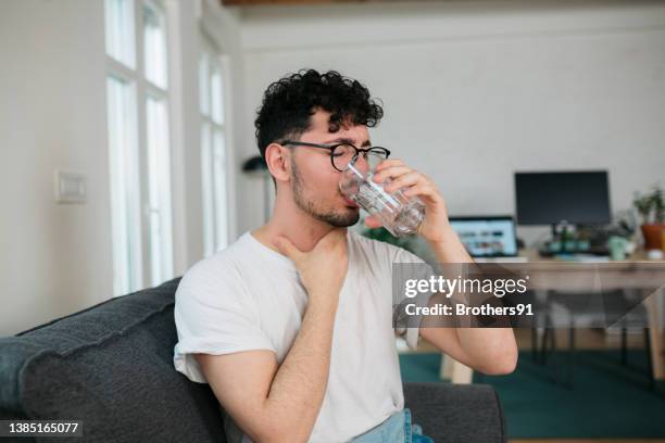 young caucasian man feeling sick at home - sore throat stock pictures, royalty-free photos & images