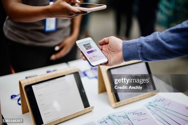 el miembro del personal de la conferencia escanea un código qr del asistente a su llegada al sitio de check-in - register fotografías e imágenes de stock