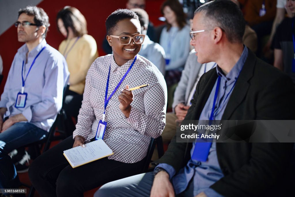 Businesspeople laughing and talking in between breaks during conference event