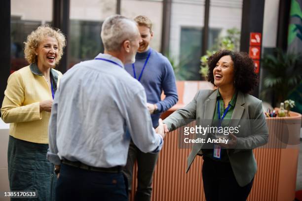 business people greet each other during a coffee break at a conference - ontbijt stockfoto's en -beelden