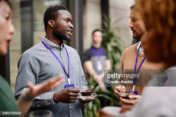 unternehmer trinken schwarzen kaffee, während sie mit kollegen im kongresszentrum stehen - conference stock-fotos und bilder