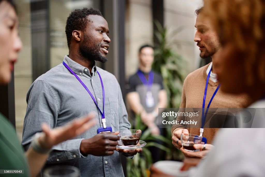 Entrepreneurs drinking black coffee while standing with colleagues in convention center