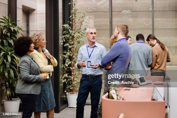 business people enjoying conversation with diverse colleagues during break from conference - party food and drink stock pictures, royalty-free photos & images