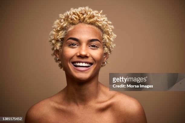 happy african american woman with blonde curly hair against brown background. - real people lifestyle photos et images de collection