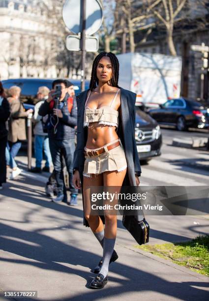 Model Cindy Bruna seen wearing beige cropped top, mini skirt, grey coat, knee high socks, black bag, loafers outside Miu Miu during Paris Fashion...