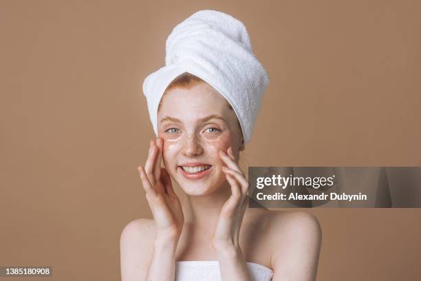 happy young smiling woman model with facial patches over beige background in studio copy space. emotional girl skin care using cosmetic product - woman with towel spa stock pictures, royalty-free photos & images