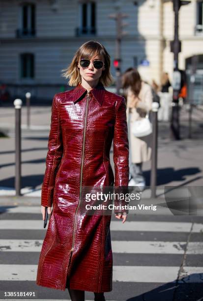 Anya Ziourova seen wearing bordeaux red colored zipper coat, sheer tights, white heels outside Miu Miu during Paris Fashion Week - Womenswear F/W...