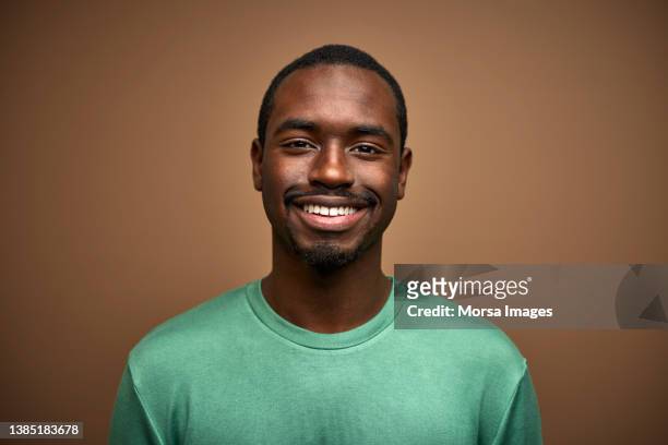 portrait of smiling man over brown background - green tee stock pictures, royalty-free photos & images