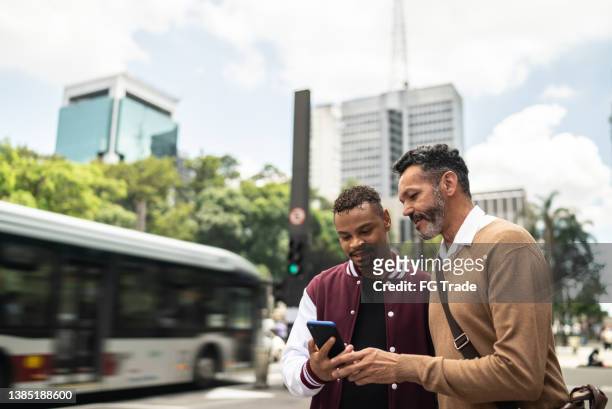 couple gay utilisant le téléphone portable dans la rue - man showing phone photos et images de collection